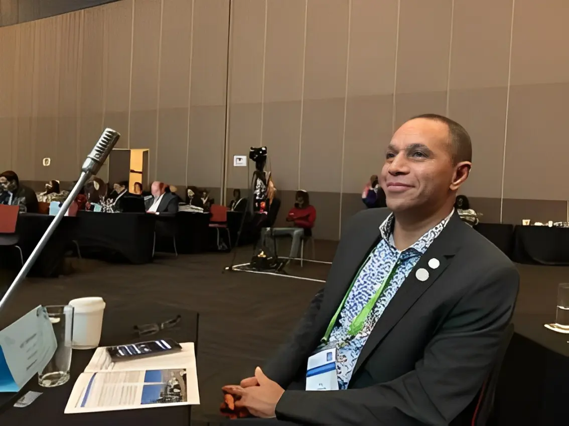 17b4ca0c6355fbce631b46c954080e29 A man sitting in front of microphones at an event.