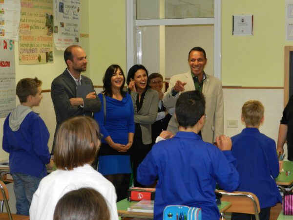 A group of people standing around in front of some kids.