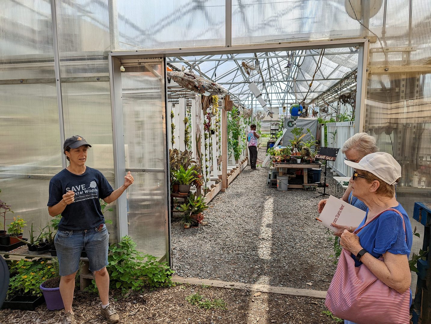 A group of people standing in front of a greenhouse.