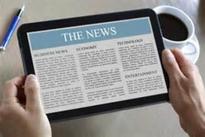 615097cd53a6653b7af7177fb06d507a A person holding an ipad with the news on it.
