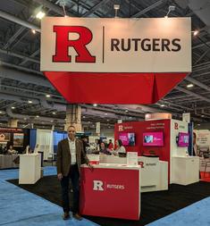 A man standing in front of a rutgers sign.