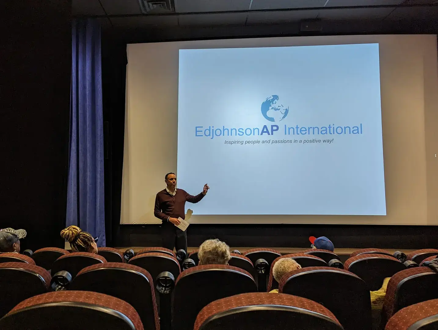 A man standing in front of a projector screen.