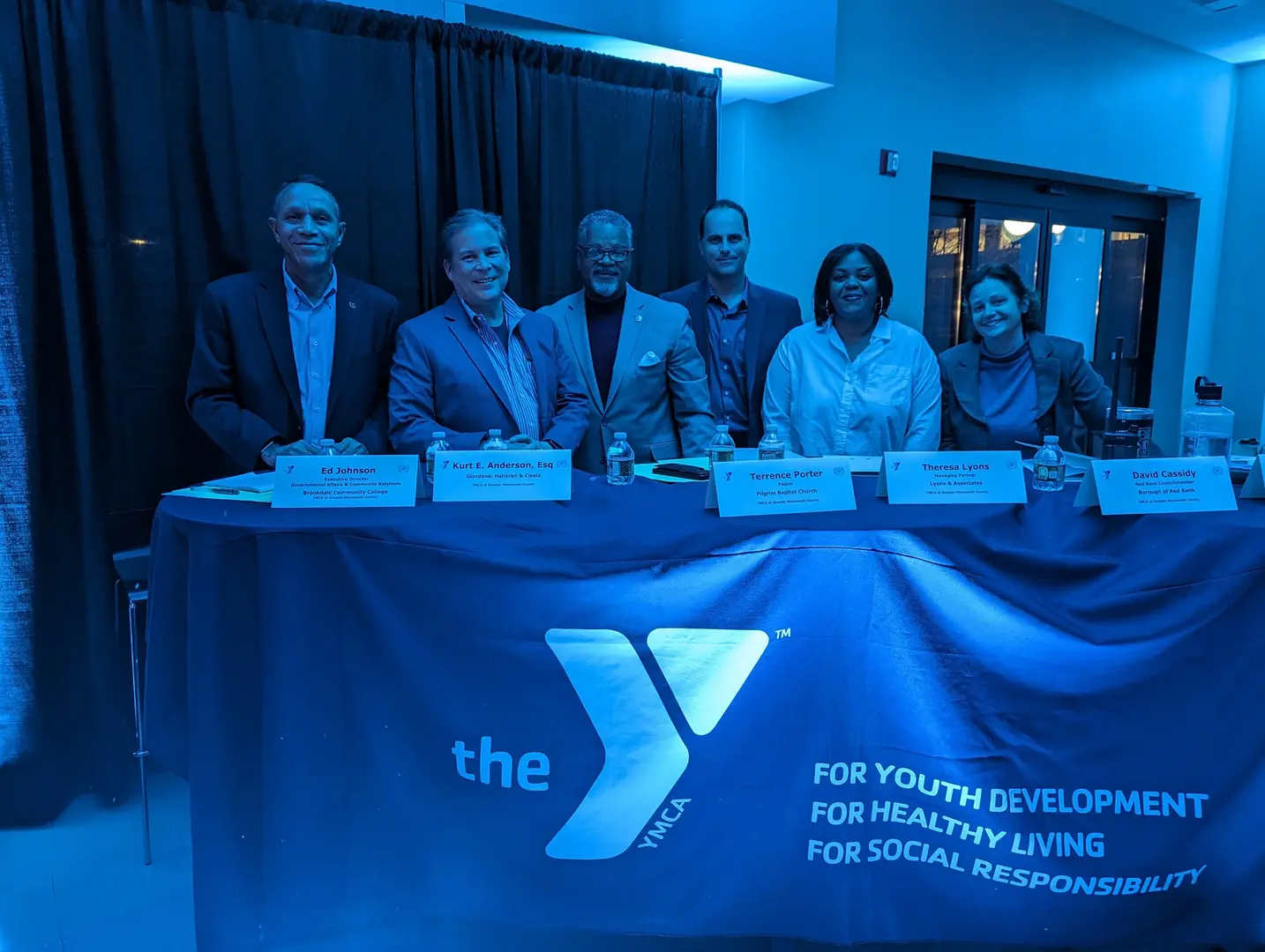 A group of people sitting at a table with a sign.