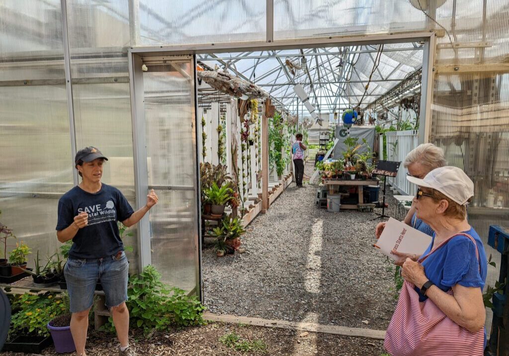 A group of people standing in front of a greenhouse.
